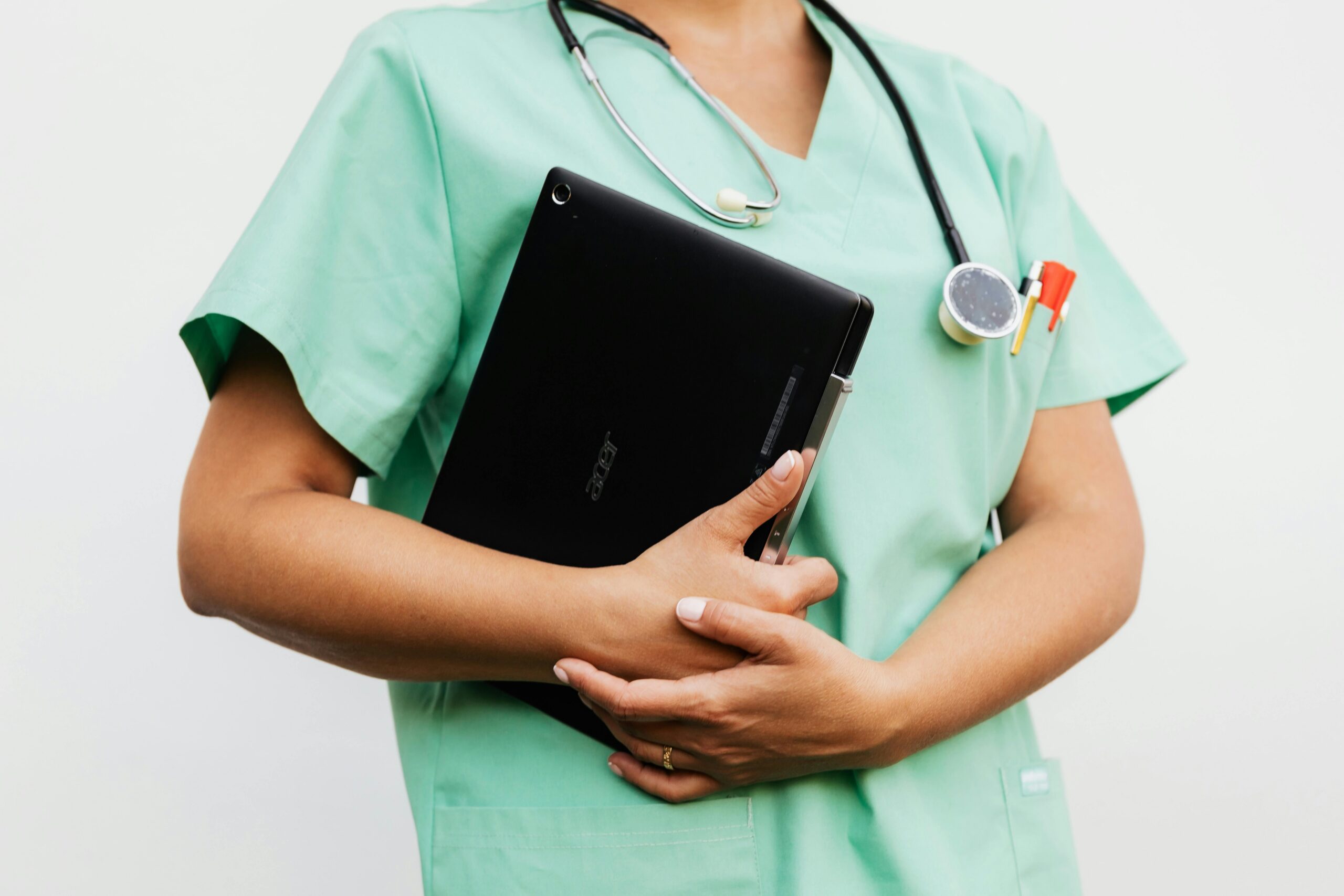 A hospital staff member holding a tablet for their Mobile App for Business while wearing mint colored scrubs.